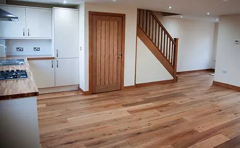 A kitchen with a stove top oven sitting under a stair case.